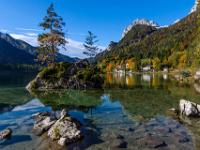Bäume auf Felsinsel vor herbstlicher Landschaft